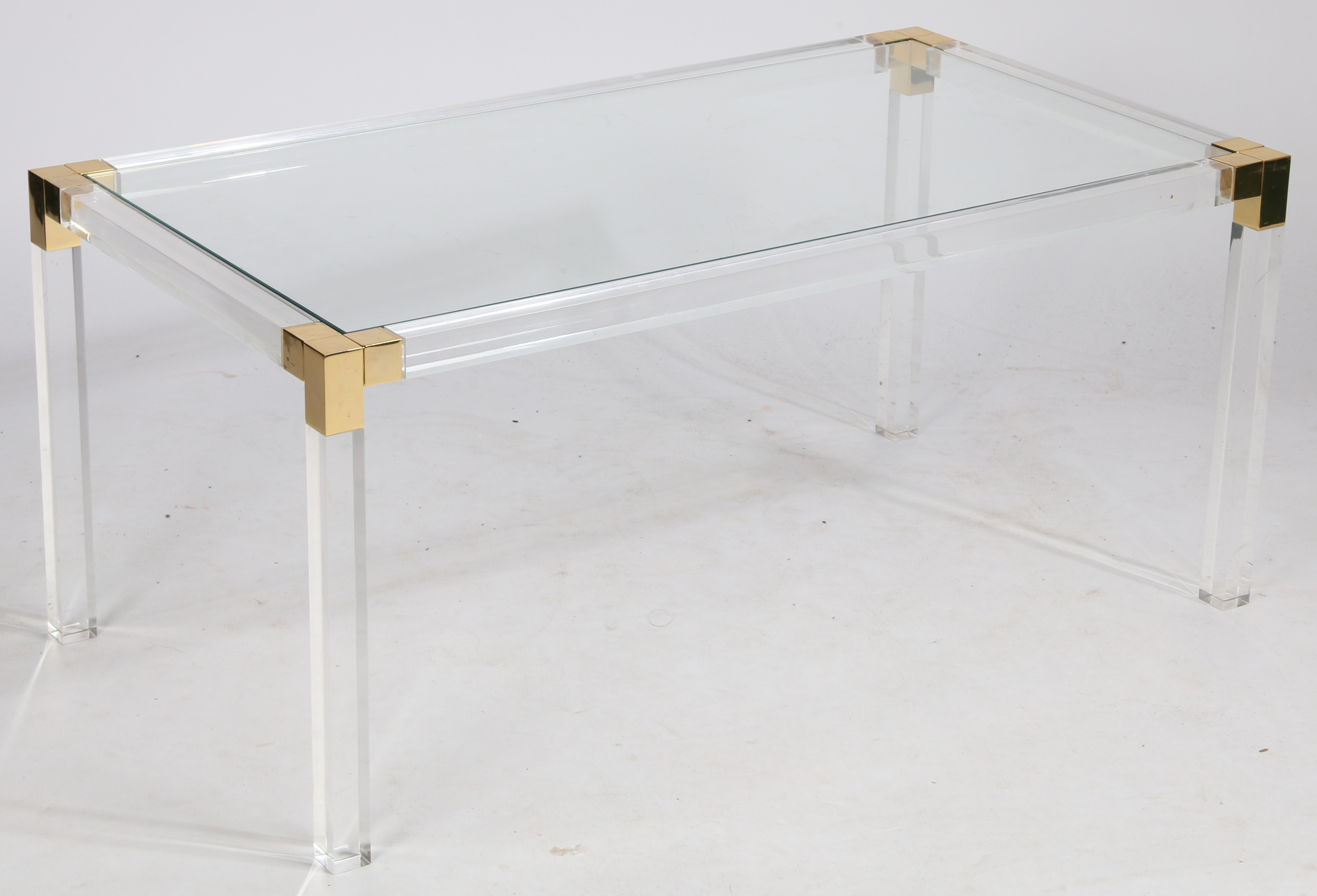 A rectangular coffee table, circa 1970s, the glass top supported on Lucite and gilded metal finished