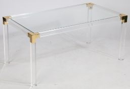 A rectangular coffee table, circa 1970s, the glass top supported on Lucite and gilded metal finished