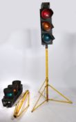 A pair of traffic lights by Pike Signals Ltd., raised on yellow tripod stands. Plaques to the