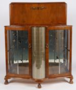 A circa 1970s Rivington walnut veneered cocktail cabinet with mirrored interior, rotating bottle