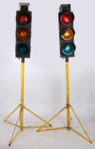 A pair of traffic lights by Pike Signals Ltd., raised on yellow tripod stands. Plaques to the