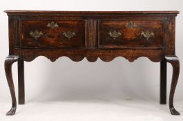 A George III oak dresser base, the two frieze drawers with shaped backplates and escutcheons above a