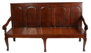 A George III oak settle, the back with five fielded panels above a later plank seat, raised on