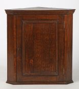 A George III style hanging corner cupboard, the panelled door opening to reveal a shaped front