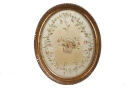 An early 19th century silk work embroidery, of oval form, centred with a basket of flowers within