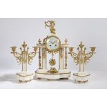 A French white marble and gilt brass three piece clock garniture, the dial surmounted with putti,