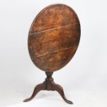 A George III oak occasional table, the circular tilt-top above a baluster stem, tripod legs and