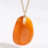 A polished amber pendant with gold coloured metal mount and non-contemporary necklace, the pendant