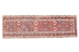 An Anatolian runner rug, with a red orange and blue ground set with floral guls and multiple
