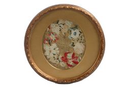 A small 19th Century needlework picture depicting an arrangement of flowers, housed in an oval mount