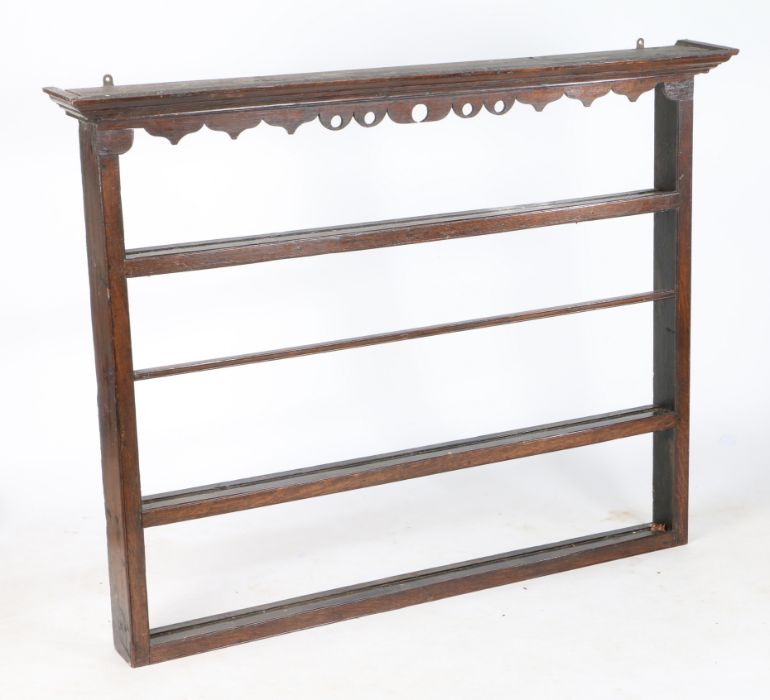 An 18th Century oak plate rack, with swept pediment, arch and roundel carved frieze above three
