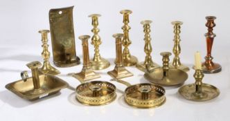 A collection of 19th century and later brass candlesticks, chambersticks and a wall mounted