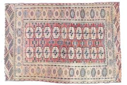 A Turkish rug, with a red cream and blue ground, set with two rows of elephants foot medallions