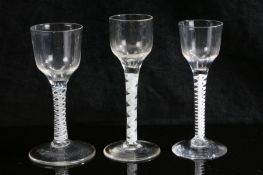 Three 18th Century air twist glasses, all with multiple white glass air twist stems, the largest