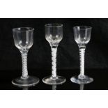 Three 18th Century air twist glasses, all with multiple white glass air twist stems, the largest