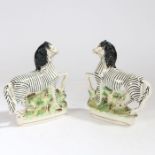 A pair of 19th century Staffordshire zebras, modelled wearing reigns and on naturalistic bases, 22cm