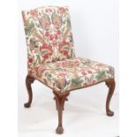 A George II mahogany side chair, upholstered in a foliate material, raised on scroll carved cabriole