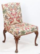 A George II mahogany side chair, upholstered in a foliate material, raised on scroll carved cabriole