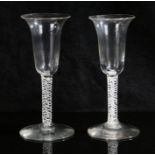 A near pair of 18th Century air twist glasses, the bowls with flared rims above white spiralling