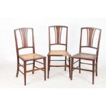 Three Edwardian bedroom chairs, with pierced tapering splat backs and cane seats, on square tapering