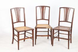 Three Edwardian bedroom chairs, with pierced tapering splat backs and cane seats, on square tapering