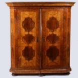 A 18th century German walnut and stained cupboard, having walnut and inlaid doors and sides raised