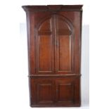 An oak barrel-back standing corner cupboard, circa 1800 The bold moulded cornice with key-stone,