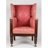 A Regency mahogany and upholstered wing arm chair, upholstered in a red floral fabric, above