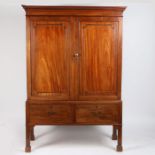 An Irish Regency mahogany linen press on stand, having a out swept cornice above two paneled doors