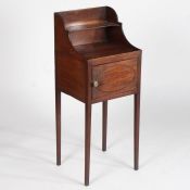 A George III mahogany bedside cupboard, having a raised gallery above a single door