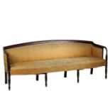 A Regency mahogany and upholstered three seater settee, having a arched back raised on down swept