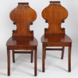 A pair of regency mahogany hall chairs, circa 1810, with a gadrooned top and a scroll carved back,