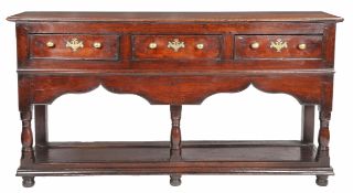 A George II oak open dresser base, Montgomeryshire, circa 1740 Having a boarded top, and three