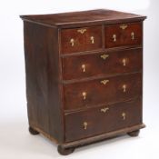 A George III oak chest of drawers, having two short over three long drawers raised on bun feet,