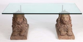 A 20th Century coffee table, with a rectangular glass top above two reconstituted reclining lions,
