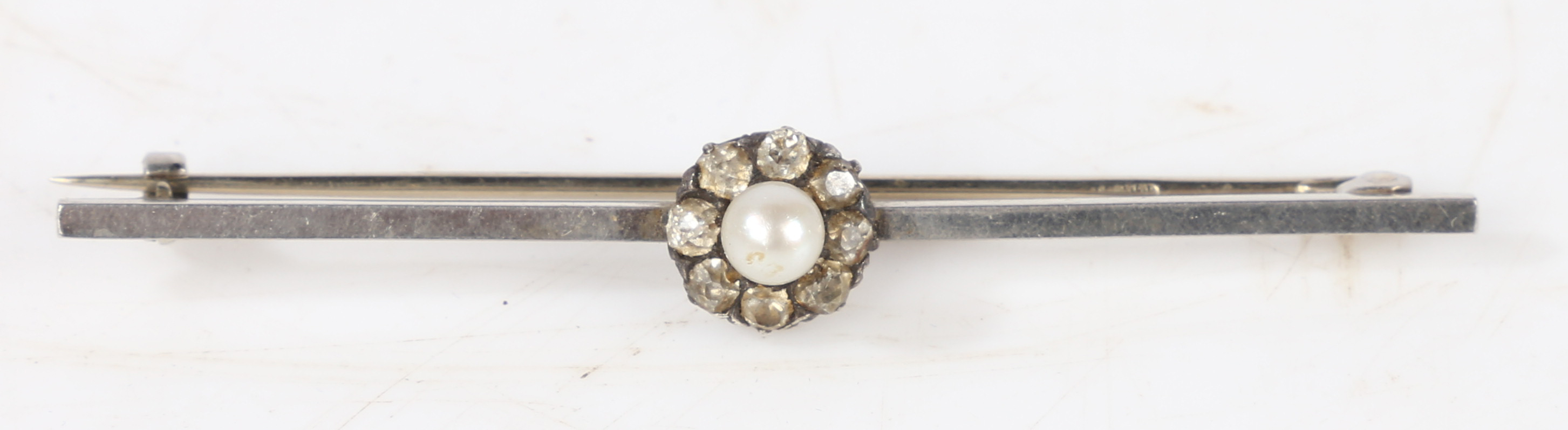 A platinum bar brooch with central pearl surrounded by a band of eight diamonds, 57.6mm wide, 4.6g