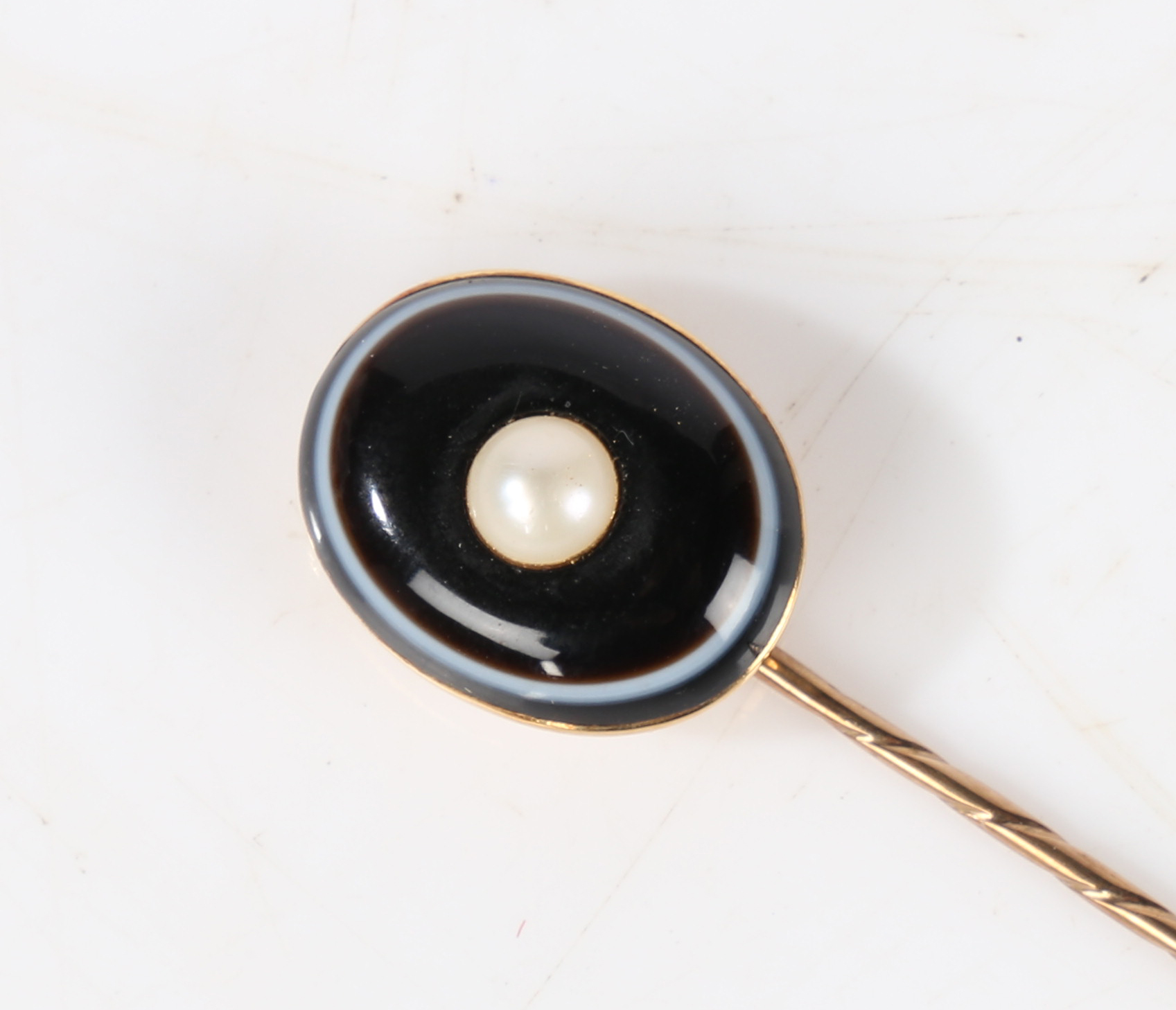 A yellow metal, banded agate and pearl set stick pin, the head set with an oval banded agate centred