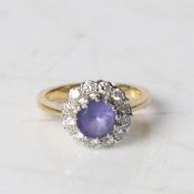 An 18 carat gold, tanzanite and diamond ring, the central round facet cut tanzanite surrounded by