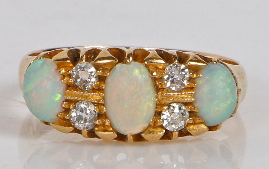 An 18 carat gold, opal and diamond ring, the head set with three oval opals interspersed by four