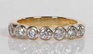 An 18 carat gold and diamond ring, set with seven round brilliant cut diamonds, ring size K 1/2, 5.