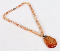 An agate bead necklace and pendant, the pendant with pierced foliate and fruit decoration, with