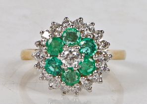 An 18 carat gold, emerald and diamond cluster ring, set with a central diamond surrounded by a