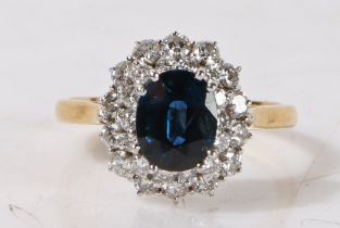 An 18 carat gold, sapphire and diamond cluster ring, the central oval facet cut sapphire