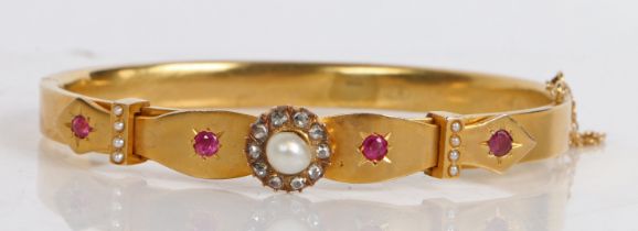 A Victorian yellow metal, pearl, diamond and ruby bangle, with central pearl surrounded by a band of