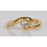 An 18 carat gold and diamond solitaire ring, the crossover band set with a single round brilliant