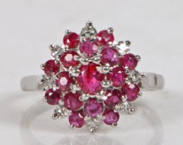 An 18 carat white gold, ruby and diamond cluster ring, the central ruby surrounded by a band of