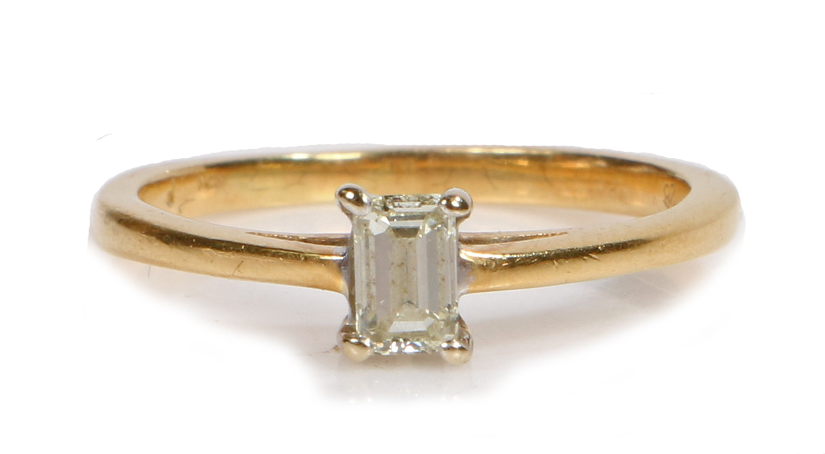 A yellow metal and baguette diamond solitaire ring, set within four claws, ring size K, 2.2g