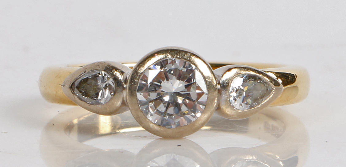 An 18 carat gold and diamond ring, the central round brilliant cut diamond flanked by two teardrop