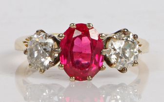 An 18 carat synthetic ruby and diamond ring, the central oval faceted synthetic ruby flanked by