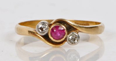 An 18 carat gold, ruby and diamond ring, the scrolled head set with a central ruby flanked by two